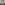 A portrait of a smiling man wearing a navy blue suit, white shirt, and black tie, set against a neutral gray background.